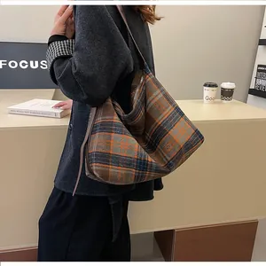 Détail du grand sac cabas à carreaux avec bandoulière en cuir porté par un mannequin