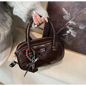 Detail of a shiny dark brown Boston bag with a glossy finish and vintage star charms