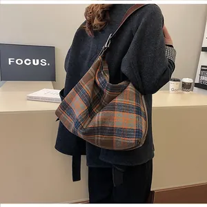 Détail du sac hobo à carreaux avec bandoulière en cuir brun dans un cadre urbain