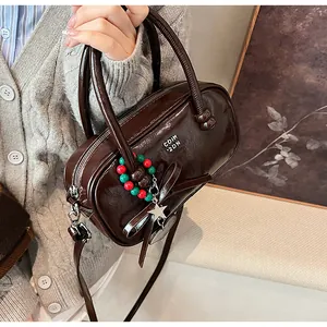 Detail of dark brown glossy handbag with large bow and colorful star charm accessory