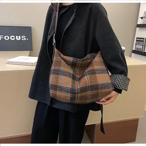 Détail macro du sac hobo à carreaux vintage avec bandoulière en cuir pour femme en hiver