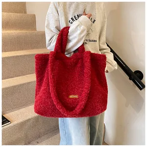 Dettaglio di borsa tote in peluche rosso con consistenza pelosa e etichetta marrone