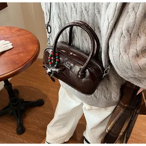 Deep brown glossy patent leather Boston bag with star charm worn as a crossbody bag