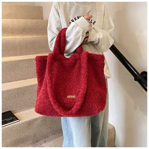 Dettaglio della borsa tote in peluche rosso con consistenza morbida e toppa in pelle marrone
