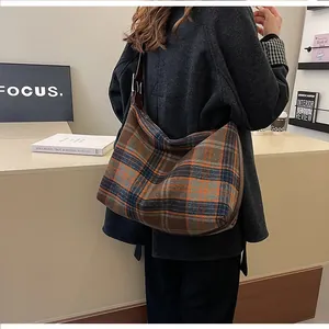 Détail du sac cabas en tweed à carreaux avec bandoulière à nœud porté par un mannequin