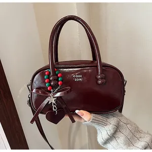 Detail of red glossy patent leather handbag with bow and charms on a light background