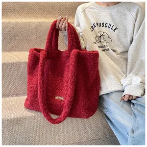 Dettaglio della borsa tote in peluche rossa con etichetta „our fave“ in scena lifestyle