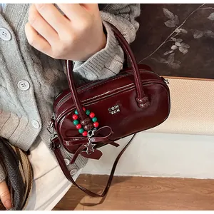 Detail of burgundy patent leather satchel bag with silver logo and decorative beads