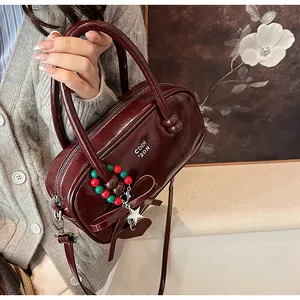 Detail of burgundy patent leather bag with star and heart charms and logo embossing