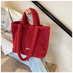 Dettaglio della borsa tote in peluche rosso in ecopelliccia con etichetta in pelle e manico