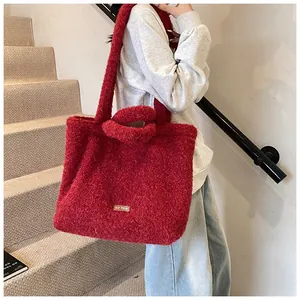 Dettaglio della borsa tote rossa in peluche con tracolla e etichetta in tessuto