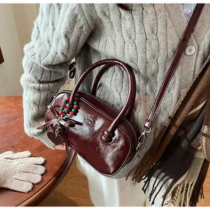 Detail of red-brown glossy faux leather bowling bag with heart charm and bow decor