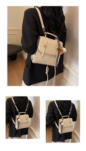 Detail view of a cream textured leather mini handbag with silk scarf and baseball charm