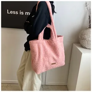 Dettaglio della borsa tote in peluche rosa con texture morbida e placca in metallo dorato