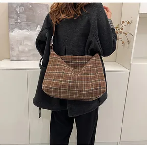 Détail d'un sac cabas à carreaux marron avec texture laineuse et bandoulière en cuir