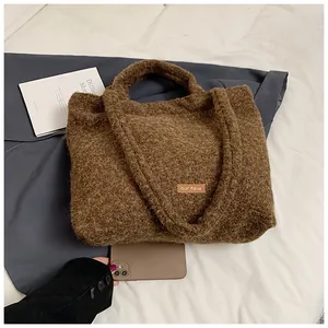Dettaglio borsa shopper marrone in peluche con patch in pelle e smartphone di misura