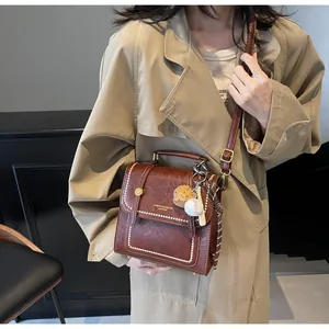 Detail of red-brown retro leather handbag with white stitching and baseball charm