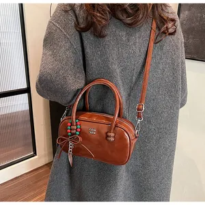 Detail of glossy caramel leather handbag with vintage beaded charm and metal zipper