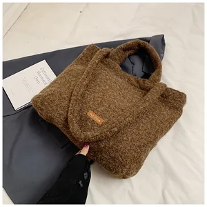 Dettaglio della borsa tote marrone in peluche con toppa in pelle su sfondo di blazer