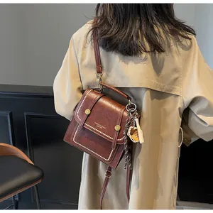 Close-up of retro brown leather handbag with pearl edge detail and baseball charm