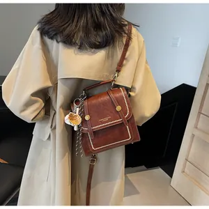 Detail of vintage brown leather handbag with pearl rivets and cute cat paw pendant charm