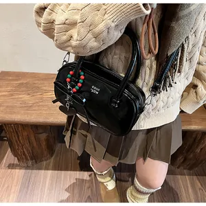 Detail of black patent leather crossbody bag with red and green beaded charms