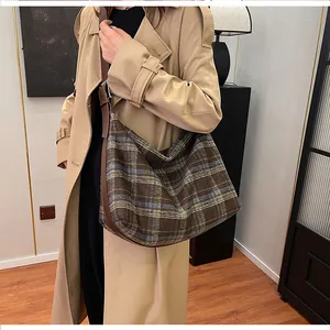 Gros plan d'un sac à bandoulière vintage à carreaux avec une lanière en cuir marron