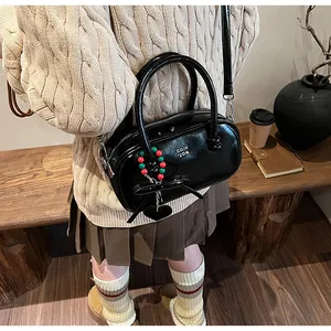 Close-up of black patent leather handbag with luxury metal logo and colorful charms