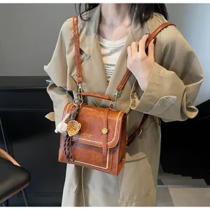 Detail view of brown vintage PU leather bag with white stitching and baseball charm