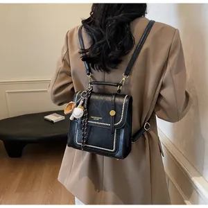 Detail of a vintage black leather handbag with pearl edge trim and baseball charm accessory