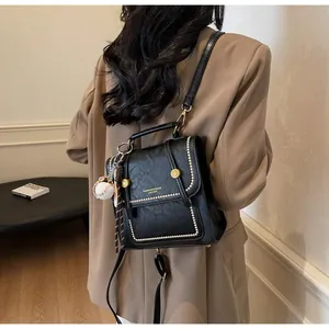 Detail of retro black PU leather handbag with gold metal clasp and baseball keychain