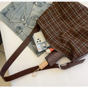 Détail du sac hobo à carreaux marron avec fermeture éclair et bandoulière en cuir