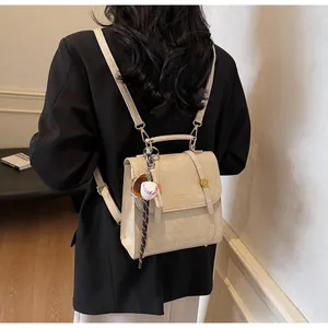Detail of cream vintage leather bag with flap closure and baseball pendant on a model