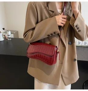 Detailaufnahme der burgunderroten Krokodil-Handtasche mit asymmetrischer Wellenklappe