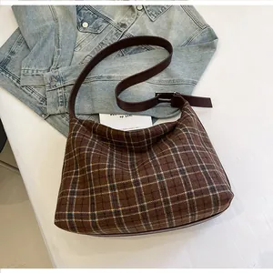 Détail du sac cabas à carreaux marron avec bandoulière sur fond de veste en jean