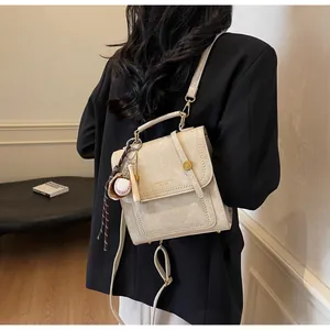 Detail of cream leather handbag with fashion lettering and baseball charm accessory