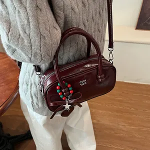 Winter red patent leather crossbody bag with charms and adjustable strap on a model