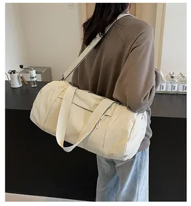 Detail of beige cylinder sports bag showing adjustable strap and textured nylon fabric