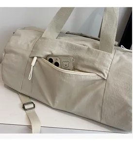 Detailed view of the external zipper pocket on a beige nylon sports gym bag for storage