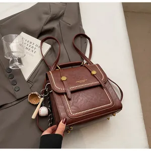 Detail of vintage brown leather handbag with gold rivets and baseball charm
