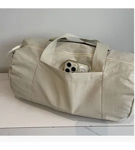 Detail of beige nylon yoga bag showing a functional front pocket holding a smartphone