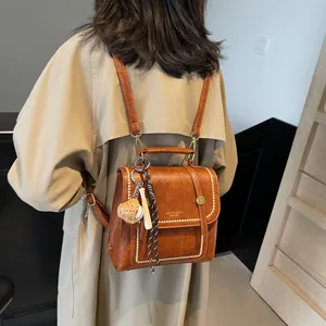 Retro brown leather backpack with contrast stitching and baseball bag charm detail
