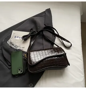 Detail der glänzenden dunkelbraunen Krokodilstruktur auf einer modischen Schultertasche