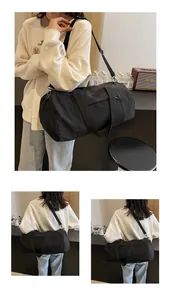 Close-up of black nylon barrel bag featuring durable metal hooks and adjustable strap