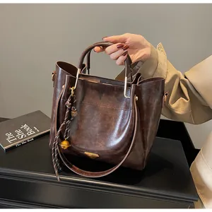 Detail of vintage brown tote bag with metal bell charm and smooth leather texture