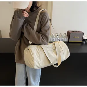 Beige cylindrical yoga bag shown in use with adjustable shoulder strap and dual handles