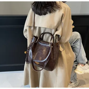 Detail of deep brown tote bag featuring vintage leather texture and gold metal accents