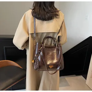 Detail of deep brown oil-wax leather tote with metallic handle and decorative pendant