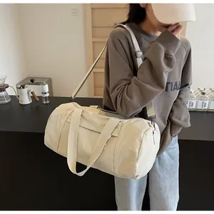 Close-up of lightweight off-white cylinder yoga bag with adjustable shoulder strap and handles
