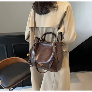 Close-up of deep brown glossy tote bag with golden hardware and tassel detail